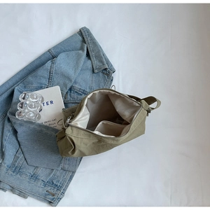 Detail view of the light green nylon bag's metal zipper and spacious fabric interior pocket