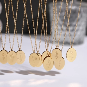 Macro detail of gold oval birth flower pendants on stainless steel necklaces