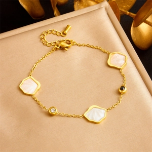 Elegant gold plated stainless steel bracelet featuring white shell pendants on a textured cushion