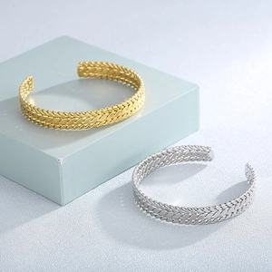 Detail showing gold and silver wheat pattern open bangles on a blue geometric stand