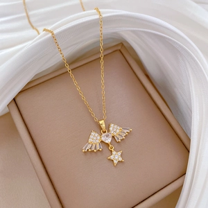 Detailed view of golden titanium heart necklace with wing and star charms on silk