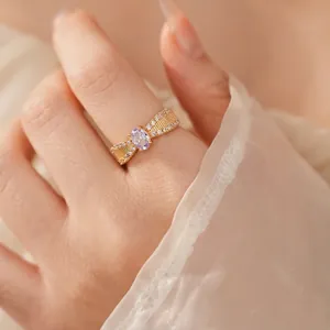 Vergoldeter Ring mit lila ovalem Stein und geflochtenem Zirkonia-Band