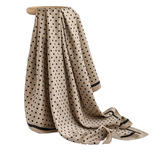 French style beige silk scarf with black polka dots and border on a wooden stand