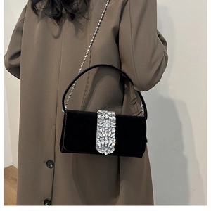 Close-up of black velvet evening bag with a large sparkling rhinestone buckle on a model