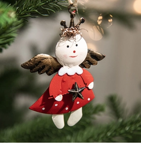 Christmas angel ornament with red dress and gold wings hanging on a festive pine branch