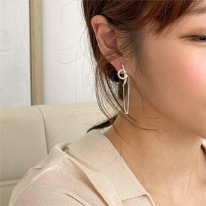 Close-up of minimalist 925 silver knot earrings with long drop chains on a model