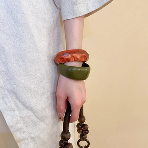 Close-up of amber marble resin faceted bangle and smooth olive green circular bracelet