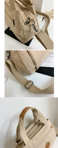 Detail of beige canvas tote bag showing metal hooks and brown leather trim accents