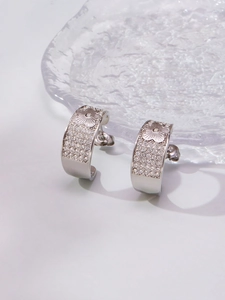 Detailed macro view of silver flower engraved earrings with sparkling white zircons