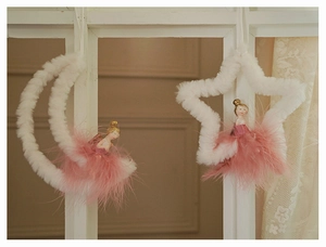 Pink feather angel ornaments hanging on a vintage white window frame with lace curtains
