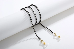 Close-up of black beaded eyewear chain with gold lobster clasps and silicone loops