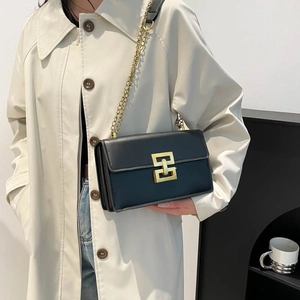 Minimalist black leather crossbody bag with gold geometric buckle and chain strap