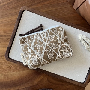 Close-up of handmade embroidered cotton linen coin purse with white zipper and cord