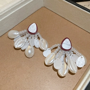 Detailed shot of starfish shell pearl earrings with tassel in a vintage jewelry box