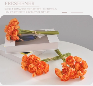 Detail of vibrant orange silk Ranunculus bouquet on white books for wedding decor