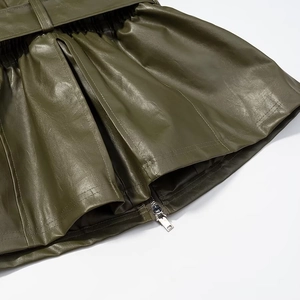 Detail of olive green faux leather skirt texture featuring zipper and belt buckle
