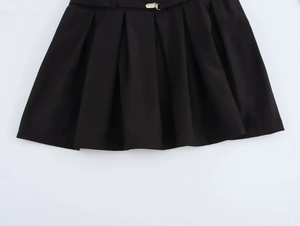 Détail du tissu plissé noir de la robe avec boucles métalliques argentées