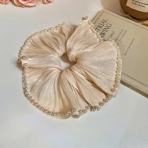 Elegant champagne gold pleated silk scrunchie with white pearl trim for high-end styling