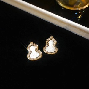 Vue macro de boucles d'oreilles hulu dorées avec émail blanc et zircons brillants