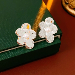 Close-up of silver flower earrings with hammered texture and white pearls on jewelry box