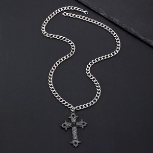 Macro view of gothic cross necklace with black gemstone and silver curb chain detail