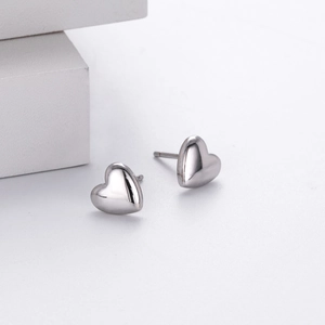 Macro shot of polished silver heart-shaped stud earrings on a geometric stone base