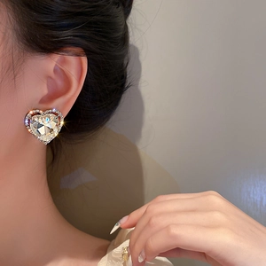 Close-up of sparkling heart-shaped rhinestone ear clip on model's ear with shiny crystal