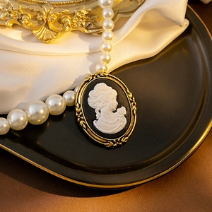 Macro view of vintage cameo pendant with baroque gold frame on a white pearl necklace