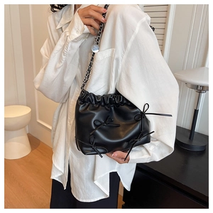 Detail of black drawstring bucket bag with leather bows and mixed chain shoulder strap