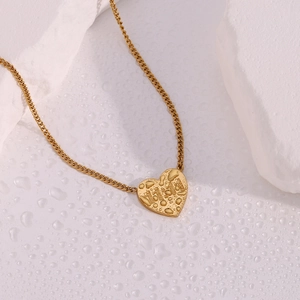 Macro shot of 11:11 angel number heart pendant in gold finish on wet white rock