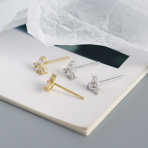 Detailed close-up of S925 silver stud earrings with zircon stones on a book page