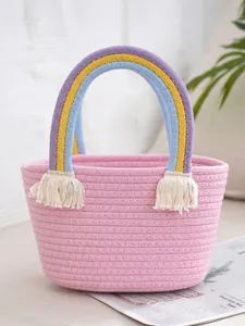 Pink hand-woven cotton rope basket with rainbow fabric handles and cream tassels