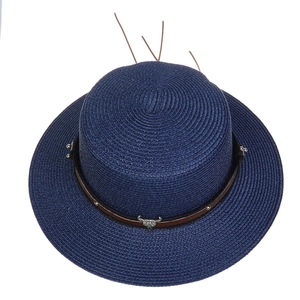 Detail of dark blue straw hat featuring brown leather band with metal bull head ornament