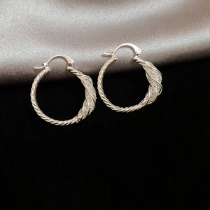 Detail of silver twisted hoop earrings featuring unique woven mesh texture and metallic finish