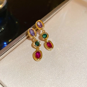 Detail of elegant gold drop earrings with purple green and red oval zircon gemstones