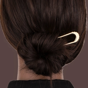 Golden U-shaped metal hair pin for retro bun styling, shown in a professional updo