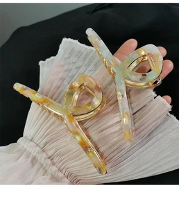Detail view of large marble texture acetate hair claw clip with golden metal spring