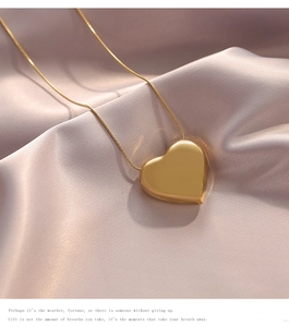 Close-up of a large gold heart pendant necklace on a soft purple satin fabric background