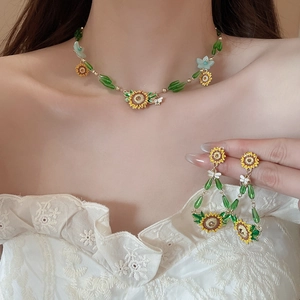 Detail of sunflower jewelry set with enamel flowers and green teardrop beads on model
