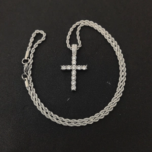 Detail of silver twisted rope chain with a crystal cross pendant on black background