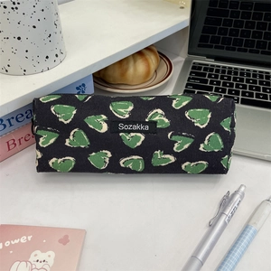 Close-up of canvas stationery bag with green heart patterns and brand label