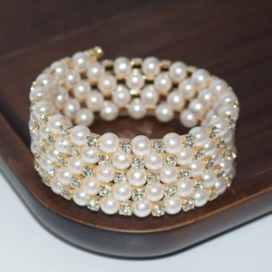 Detail of four-row pearl bracelet with sparkling rhinestones and gold metal finish