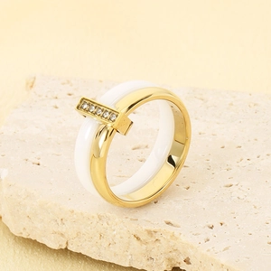 Detail view of gold titanium steel ring featuring white ceramic band and inset cubic zirconia