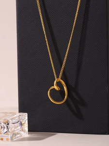 Macro detail of a 18k gold irregular hollow heart pendant on a delicate chain necklace