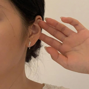 Close-up of a minimalist 925 sterling silver bow earring worn on a woman's ear