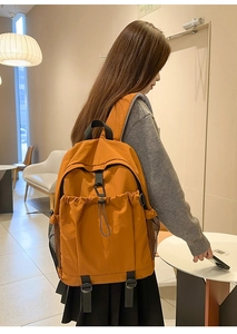 Detailansicht eines orangefarbenen Nylonrucksacks mit seitlicher Netztasche und Kordelzug