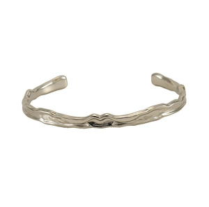 Dettaglio della trama martellata irregolare sul bracciale rigido aperto in acciaio argento