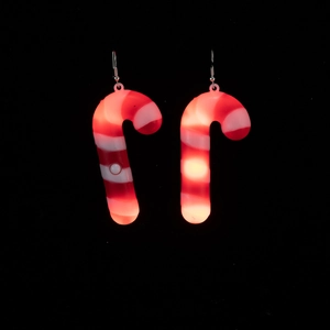 Macro shot of glowing red and white candy cane earrings for Christmas on dark background