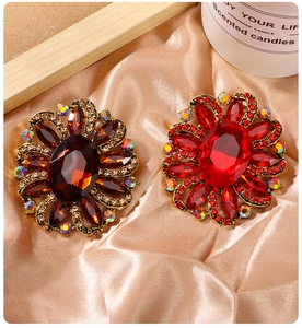 Close-up of luxury flower brooches with crystals and rhinestones on silk background