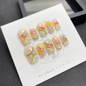 Close-up of 3D embossed citrus fruit handmade press-on nails with shiny rhinestones